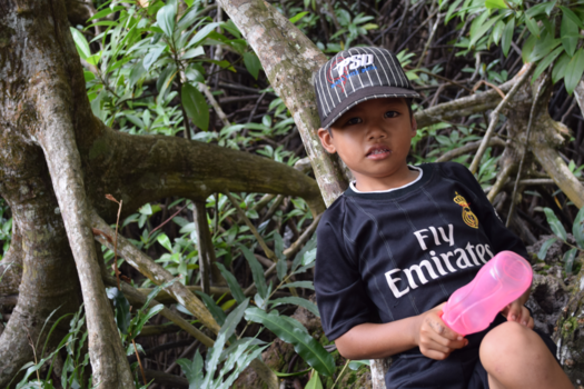 Kalimantan - Jongetje relaxt liggend op wortel mangroveboom